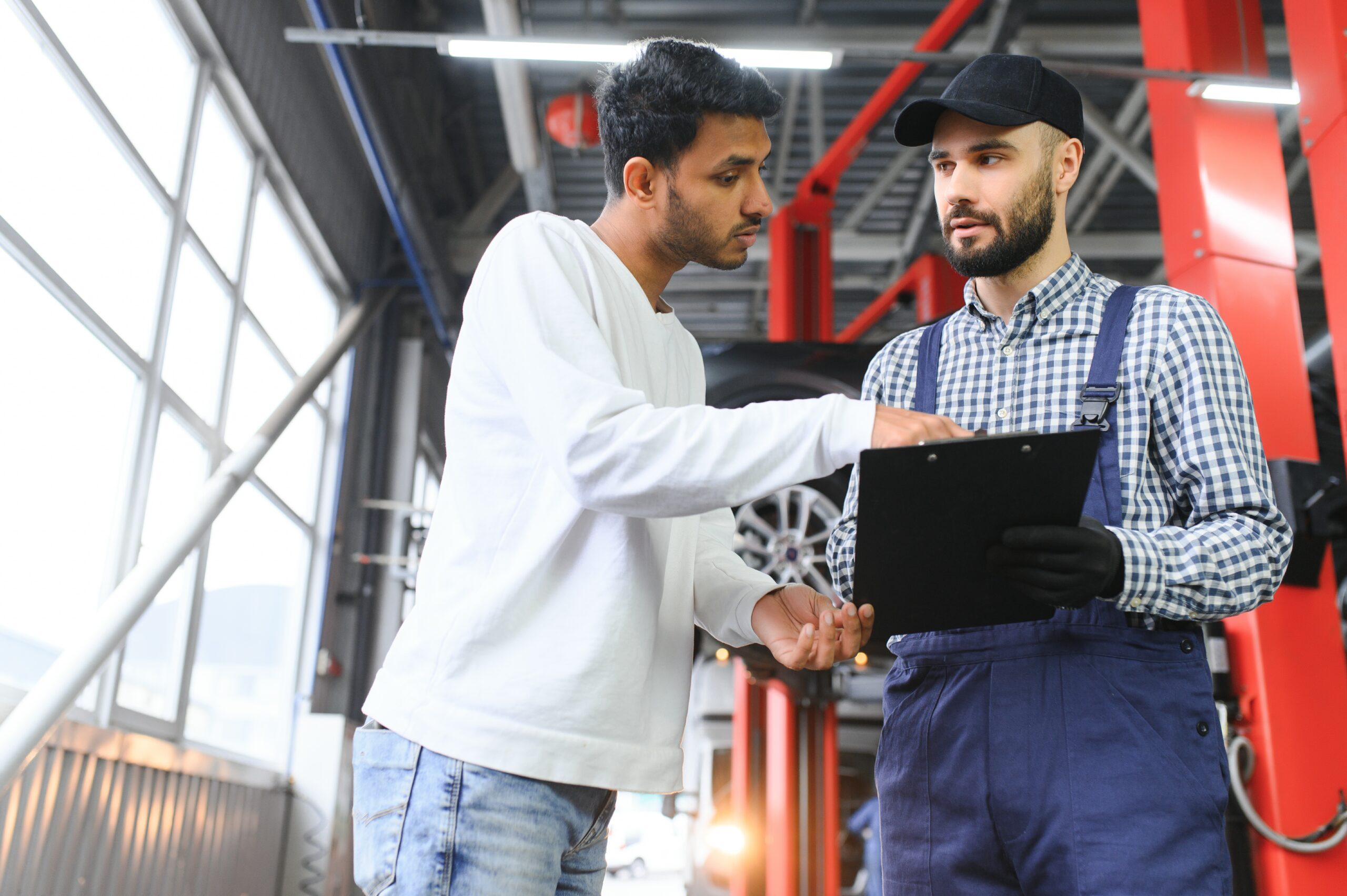A mechanic in a car service repairs an Indian man's car. Car service concept